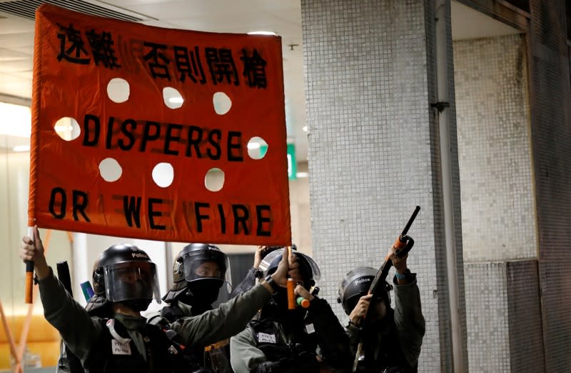 Riot police officer holds up a banner, outside a shopping mall in Tai Po in Hong Kong