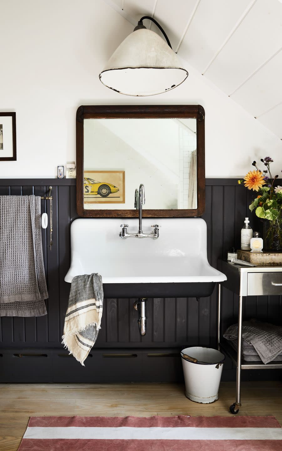 <p>This curated bathroom strikes the perfect balance between masculine and feminine. A vintage wall sink vanity and a stainless steel rolling table look thoughtfully placed against a black beadboard wall. For a similar look, try <a href="https://www.behr.com/consumer/colors/paint/color/N490-7" rel="nofollow noopener" target="_blank" data-ylk="slk:Ink Black by Behr;elm:context_link;itc:0;sec:content-canvas" class="link ">Ink Black by Behr</a>.</p>