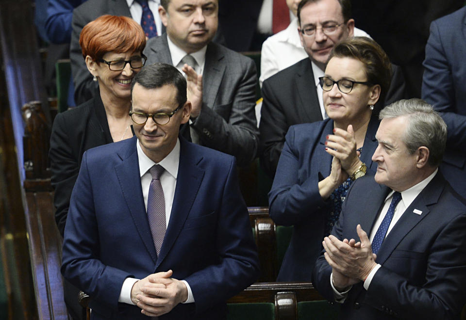 Polish Prime Minister Mateusz Morawiecki, second left, is applauded by members of his government after winning the confidence vote in the parliament, in Warsaw, Poland, Wednesday, Dec. 12, 2018. Morawiecki’s conservative government easily survived a confidence vote in parliament that the leader had unexpectedly asked for earlier in the day. Morawiecki, with the ruling Law and Justice party, had said he wanted to reconfirm that his government has a mandate from lawmakers as it pushes through its “great reforms.”(AP Photo/Alik Keplicz)
