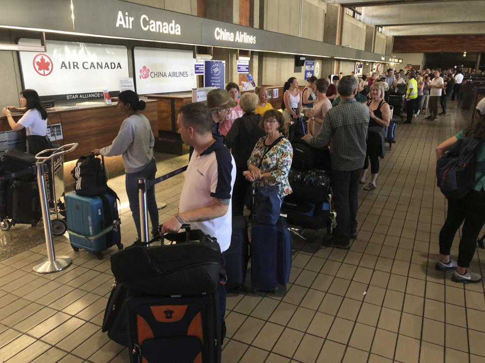 Passengers from an Australia-bound Air Canada flight diverted to Honolulu Thursday, July 11, 2019, after about 35 people were injured during turbulence, stand in line at the Air Canada counter at Daniel K. Inouye International Airport to rebook flights. Air Canada said the flight from Vancouver to Sydney encountered "un-forecasted and sudden turbulence," about two hours past Hawaii when the plane diverted to Honolulu. (AP Photo/Caleb Jones)