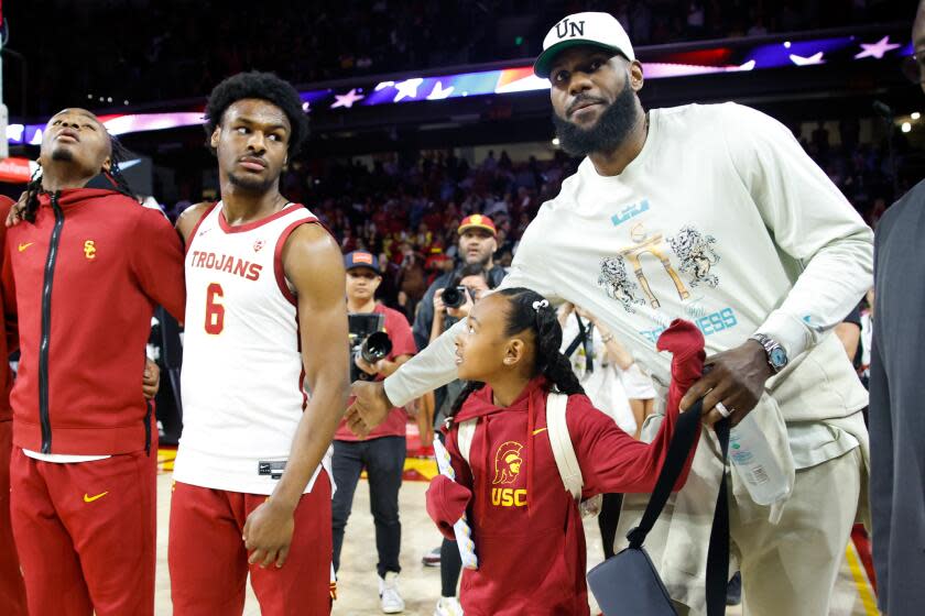 Lakers' LeBron James, right, pats the back of USC Trojans guard Bronny James (6) before the game