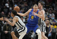 Denver Nuggets center Nikola Jokic, center, drives between San Antonio Spurs forward Keldon Johnson, front, and center Jakob Poeltl during the first half of an NBA basketball game Friday, Oct. 22, 2021, in Denver. (AP Photo/David Zalubowski)