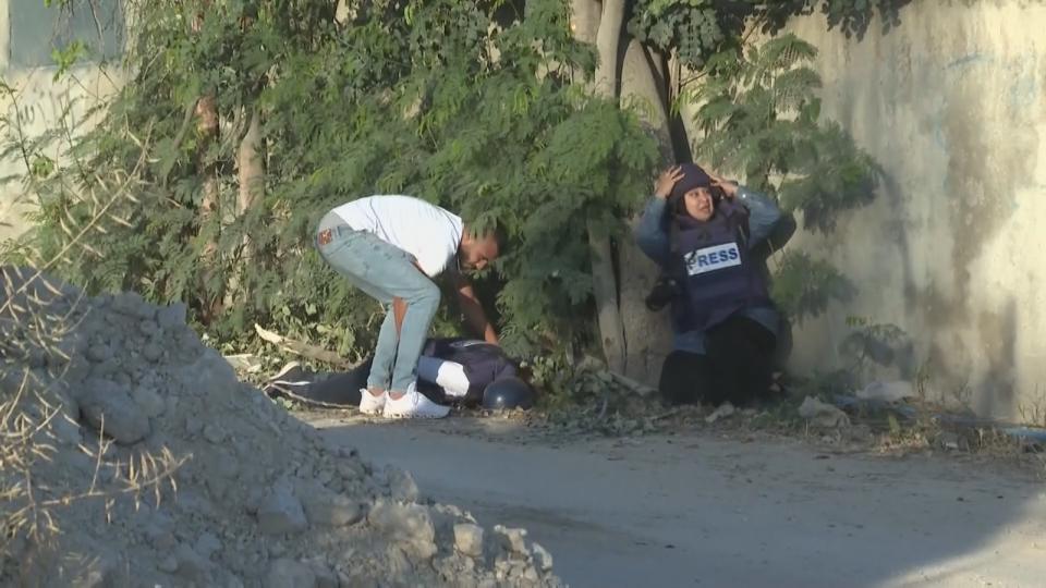 A reporter reacts as Shireen Abu Akleh is seen on the ground after being shot in Jenin, West Bank.