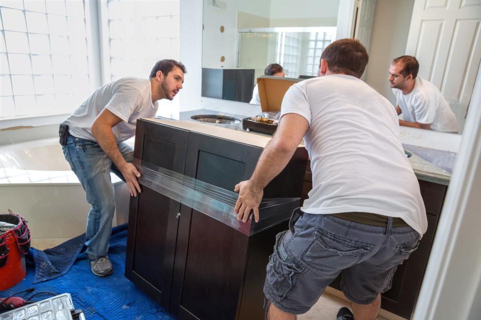 Two men install a bathroom vanity.