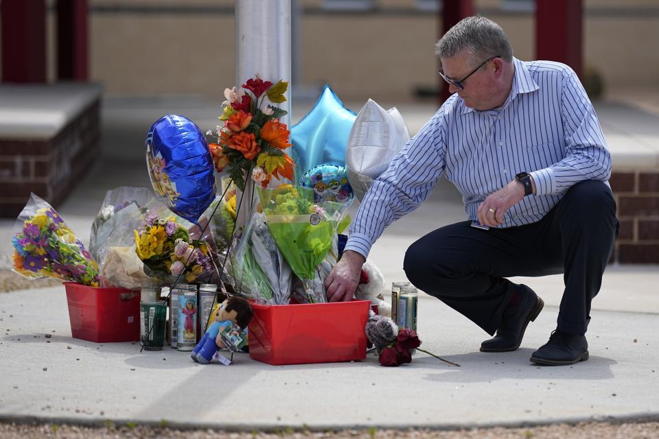 Northside Elementary Principal Pete Armstrong adjusts some flowers at a make-shift memorial outside his school on Monday, May 1, 2023, in Cleveland, Texas. The youngest of five victims of a mass shooting on Friday, Daniel Enrique Laso, 9, was a student at the elementary school. The search for a Texas man who allegedly shot his neighbors after they asked him to stop firing off rounds in his yard stretched into a third day Monday, with authorities saying the man could be anywhere by now. (AP Photo/David J. Phillip)