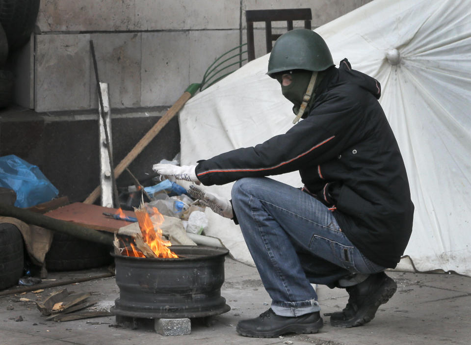 A masked pro-Russian activist warms himself next to a makeshift fire as he guards a regional administration building that they had seized earlier in Donetsk, Ukraine, Friday, April 11, 2014. Ukraine’s prime minister on Friday told leaders in the country’s restive east that he is committed to allowing regions to have more powers. Yatsenyuk Friday morning flew into Donetsk, where pro-Russian separatists are occupying the regional administration building and calling for a referendum that could prefigure seeking annexation by Russia. (AP Photo/Efrem Lukatsky)