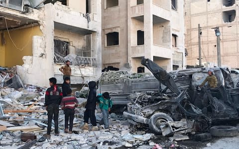 People look at the damage in the aftermath of an explosion at a base for Asian jihadists in a rebel-held area of the northwestern Syrian city of Idlib - Credit: AFP