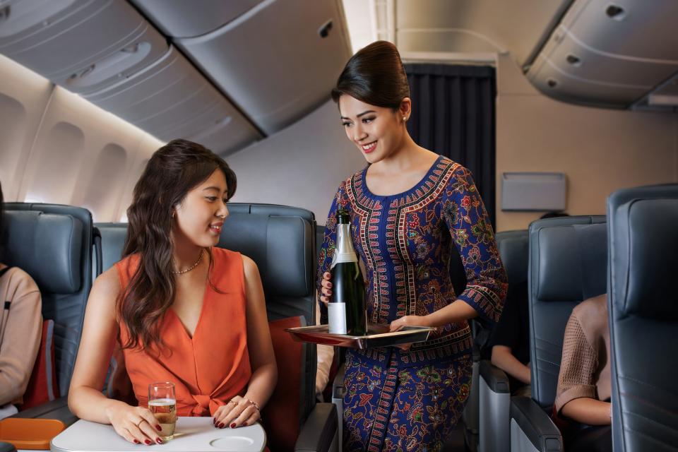 Flight attendant pouring champagne on Singapore Airlines