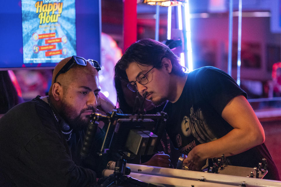 Jorge Xolalpa, left, a 33-year-old movie director from Mexico, talks to cinematographer Alonso Quintero Fregoso while filming his latest movie "Union Station" at "Trunks" gay sports bar in West Hollywood, Calif., on Tuesday, Oct. 4, 2022. Xolalpa is mired in a years-long battle over whether he can keep working legally in the United States. He is among hundreds of thousands of people waiting to learn if the program known as Deferred Action for Childhood Arrivals will be allowed to continue.(AP Photo/Damian Dovarganes)