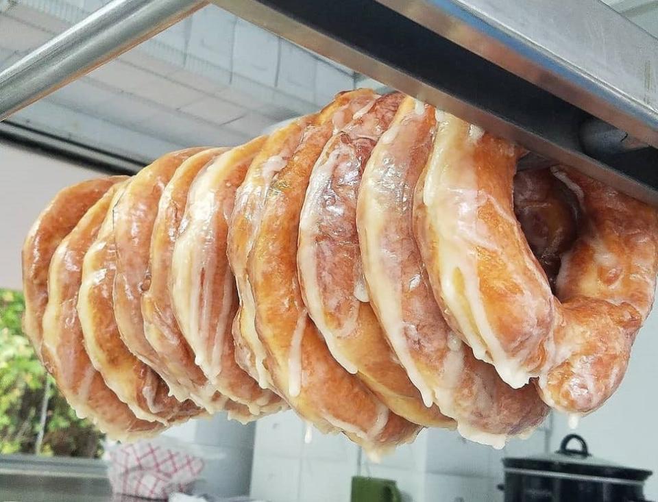 Glazed sourdough donuts hang on a dowel in Mrs. Yoder's Kitchen food truck ready to be eaten by a fan.