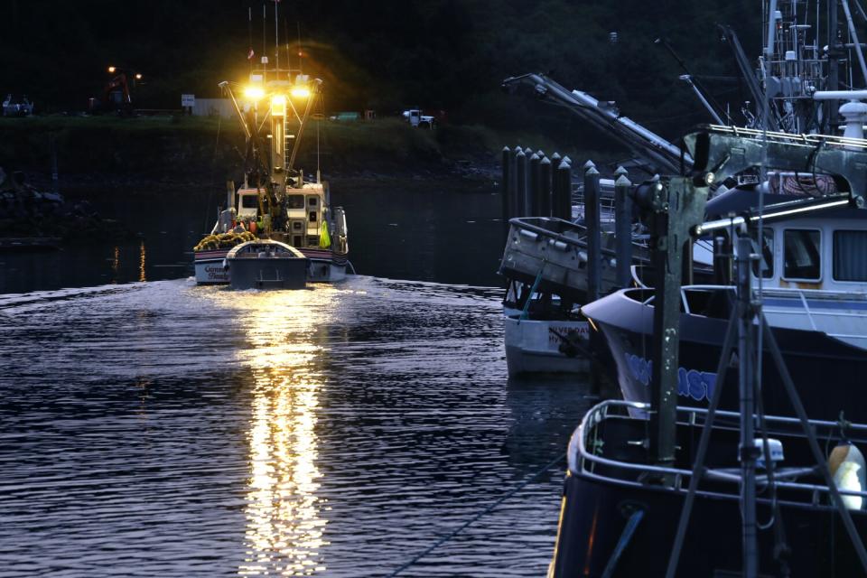 A well-lit boat leaves a harbor in the dark