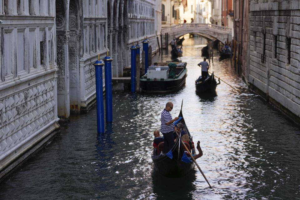 Gondoliers take tourists by the Ponte dei Sospiri (Bridge of Sighs), in Venice, Italy, Thursday, June 17, 2021. After a 15-month pause in mass international travel, Venetians are contemplating how to welcome visitors back to the picture-postcard canals and Byzantine backdrops without suffering the indignities of crowds clogging its narrow alleyways, day-trippers perched on stoops to imbibe a panino and hordes of selfie-takers straining for a spot on the Rialto Bridge or in front of St. Mark’s Basilica. (AP Photo/Luca Bruno)