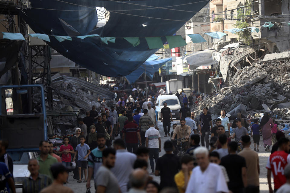 FILE - Palestinians walk in the street market of Jabaliya refugee camp, northern Gaza Strip, Wednesday, Nov. 1, 2023, after an Israeli airstrike. With the Israel-Hamas war in its second month and more than 10,000 people killed in Gaza, trapped civilians are struggling to survive without electricity or running water. Each day has become a mind-numbing cycle of searching for bread and water and waiting in lines. A sense of desperation has strained Gaza's close-knit society. (AP Photo/Abed Khaled)