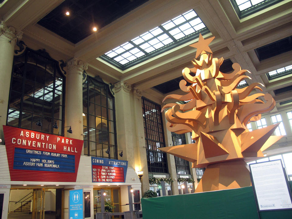 This Nov. 26, 2021 photo shows "The Giving Tree," a Christmas tree display made out of cardboard at Asbury Park NJ's Convention Hall that is delighting many in the seaside town, but dismaying others who miss the fresh-cut natural tree that is usually on display there during the holidays. (AP Photo/Wayne Parry)