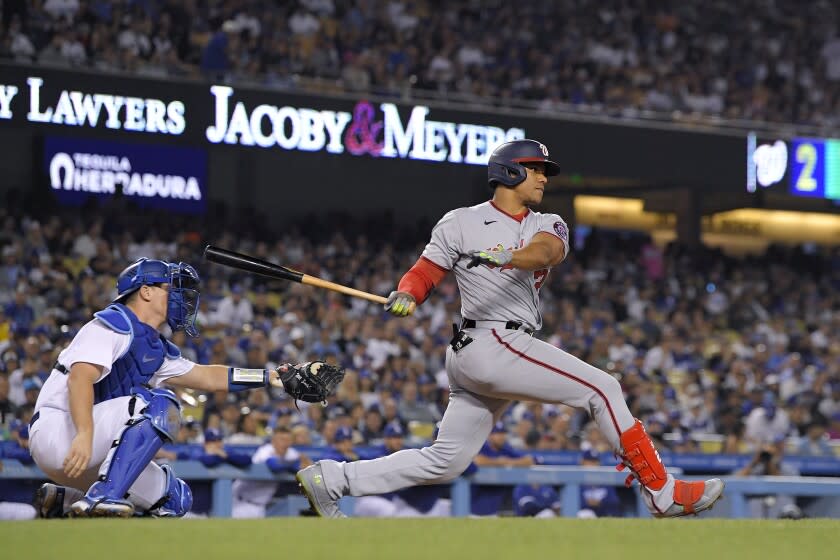 Washington Nationals' Juan Soto, right, hits a two RBI triple as Los Angeles Dodgers catcher Will Smith watches during the fifth inning of a baseball game Monday, July 25, 2022, in Los Angeles. (AP Photo/Mark J. Terrill)