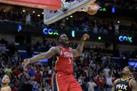 New Orleans Pelicans forward Zion Williamson (1) reacts after dunking against Phoenix Suns guard Devin Booker, bottom left, in the second half of an NBA basketball game in New Orleans, Friday, Dec. 9, 2022. (AP Photo/Matthew Hinton)