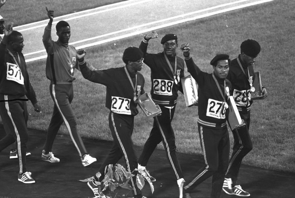 FILE - Three out of four members of the United States 4x400-meter relay team, right, hold up clenched fists as they leave the Olympic stadium after receiving their gold medals during the Mexico City Games in Mexico City, in this Sunday Oct. 21, 1968, file photo. The four, from left, are Ron Freeman (273), Vince Matthews, Lee Evans and Larry James. Lee Evans, the record-setting sprinter who wore a black beret in a sign of protest at the 1968 Olympics, died Wednesday, May 19, 2021. He was 74. USA Track and Field confirmed Evans' death. The San Jose Mercury News reported that Evans' family had started a fundraiser with hopes of bringing him back to the U.S. from Nigeria, where he coached track, to receive medical care after he suffered a stroke last week.(AP Photo/File)
