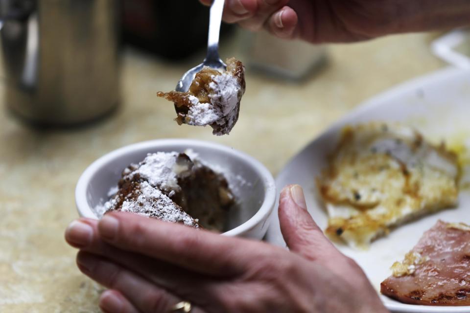 In this Monday, Jan. 28, 2013 photo, patron Cheryl Boyd of Spring Valley, Minn., eats calas cake at The Old Coffeepot Restaurant in the French Quarter of New Orleans. Tired of celebrating Mardi Gras with the same old beignets? Make the switch to calas, tangy rice fritters born to go with cafe au lait. Calas (KAH-luhs) can be tough to find these days, but they have a rich history that spans the great cuisines of New Orleans. (AP Photo/Gerald Herbert)