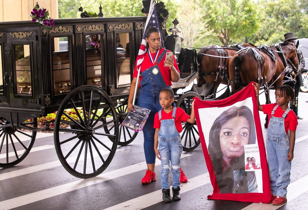 Two children hold a banner with the message “Justice For Ajike Owens” after pallbearers loaded the casket into a horse-drawn hearse. (Photo by Doug Engle/Ocala Star Banner, 2023)