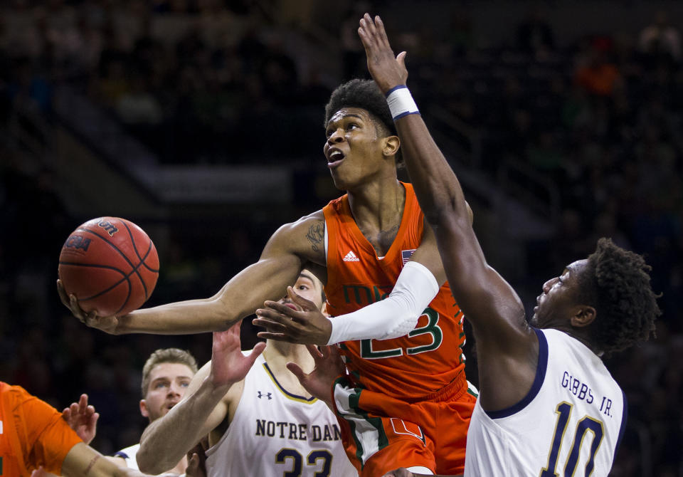 Miami's Kameron McGusty (23) goes up for a shot between Notre Dame's John Mooney (33) and Temple 'T.J.' Gibbs (10) during the first half of an NCAA college basketball game Sunday, Feb. 23, 2020, in South Bend, Ind. (AP Photo/Robert Franklin)