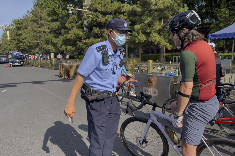 A foreigner on a bicycle talks to a police officer after he was ordered to stop for identification check at a checkpoint along a street near Tiananmen Square in Beijing, Sunday, June 4, 2023, during the 34th anniversary of China's bloody 1989 crackdown on pro-democracy protests. (AP Photo/Andy Wong)