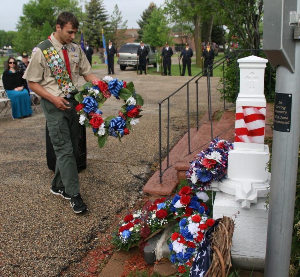 Boy Scout Bryce Falken places a wreath during the Memorial Day service Monday morning at St. Mary's Cemetery in Aberdeen.