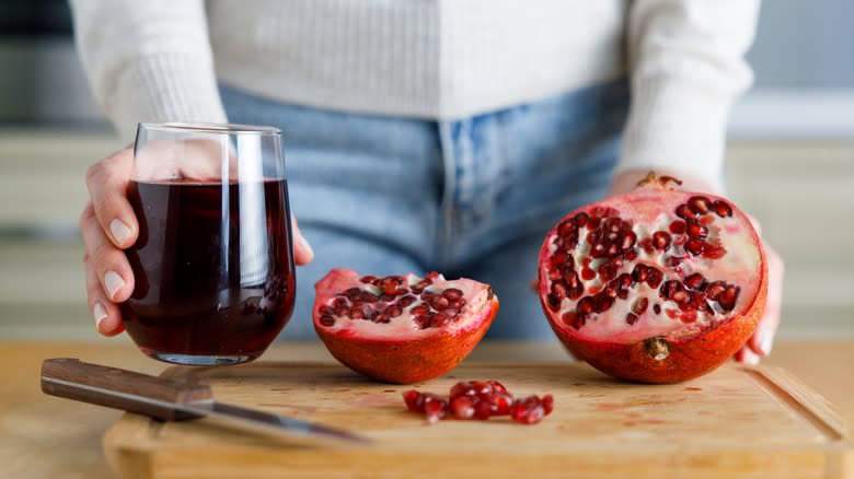 Pomegranate juice in glass next to pomegranates