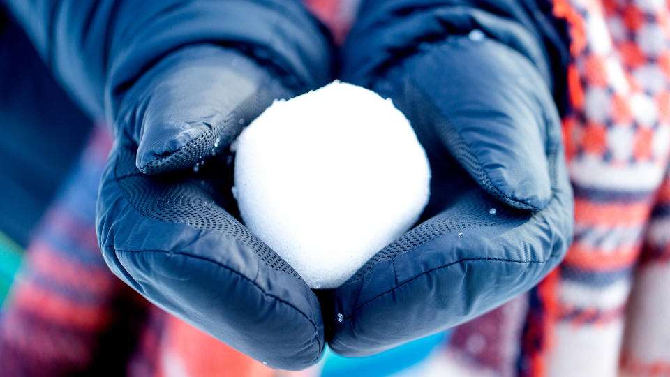 woman is holding snow ball in hands.