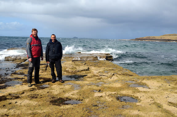 Paleontologists Steve Brusatte (right) and Tom Challands (left) stand near the dinosaur track marks on the Isle of Skye.