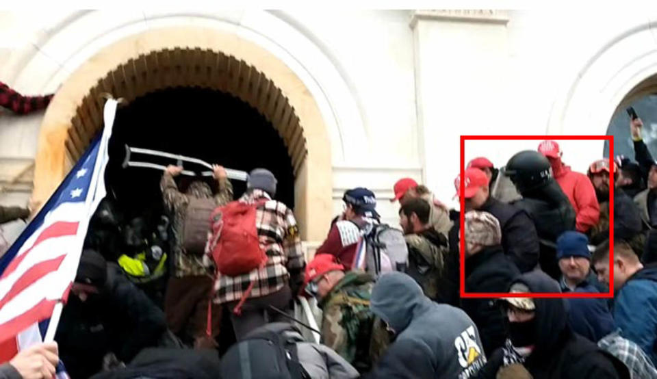 Richard Zachary Ackerman, right, wearing the U.S. Capitol Police helmet at the Capitol riots in 2021. (U.S. District Court)