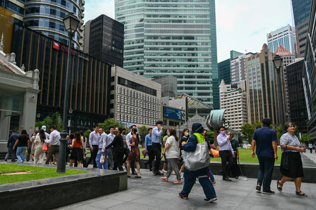 Office workers walk out for a lunch break at Raffles Place financial business district in Singapore. (PHOTO: Roslan RAHMAN / AFP)