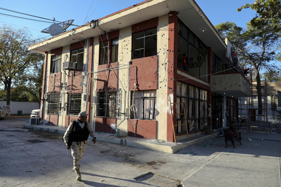 Un soldado pasa junto al ayuntamiento, lleno de agujeros de bala, en Villa Unión, México, el lunes 2 de diciembre de 2019. (AP Foto/Eduardo Verdugo)