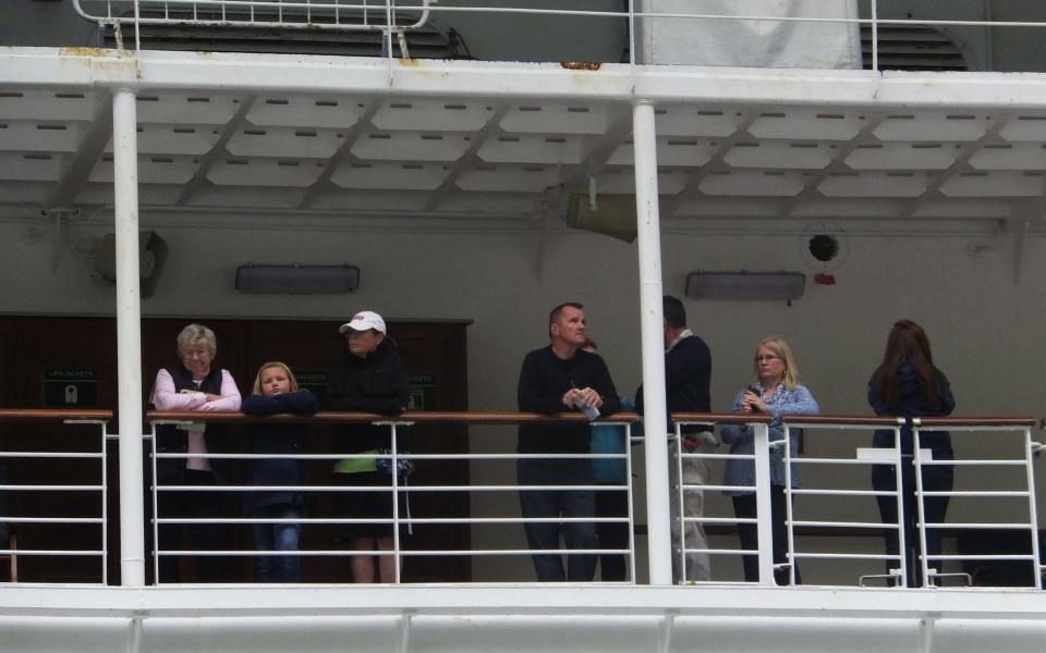 Several passengers of the Emerald Princess cruise ship bide their time on deck while waiting to disembark - Credit: AP