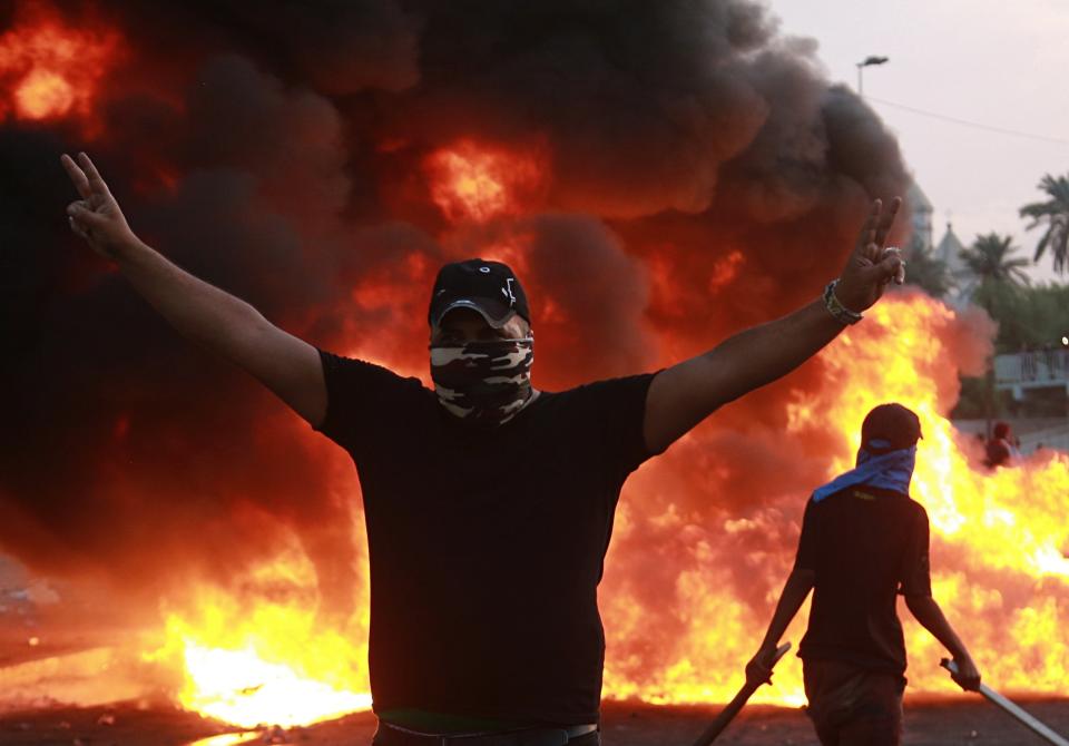 An anti-government protester flashes the victory sign during a demonstration in Baghdad, Iraq, Thursday, Oct. 3, 2019. Iraqi security forces fired live bullets into the air and used tear gas against a few hundred protesters in central Baghdad on Thursday, hours after a curfew was announced in the Iraqi capital on the heels of two days of deadly violence that gripped the country amid anti-government protests that killed several people in two days. (AP Photo/Hadi Mizban)