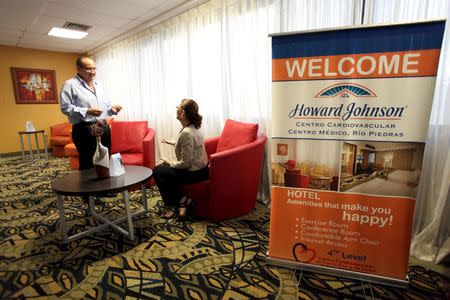 Tomas Velez (L), manager of the Howard Johnson hotel at the Cardiovascular Center of Puerto Rico and the Caribbean talks to a guest in San Juan, October 21, 2015. REUTERS/Alvin Baez