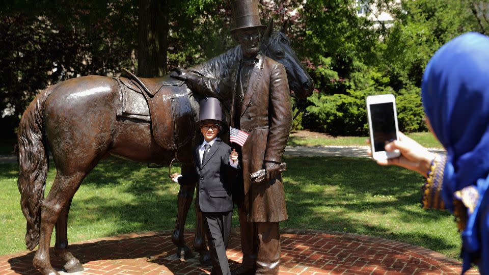 Yahya Ahmed Aflal, 6, has his photograph taken with a statue of President Abraham Lincoln following a citizenship ceremony at President Lincoln's Cottage in May 2016. - Chip Somodevilla/Getty Images