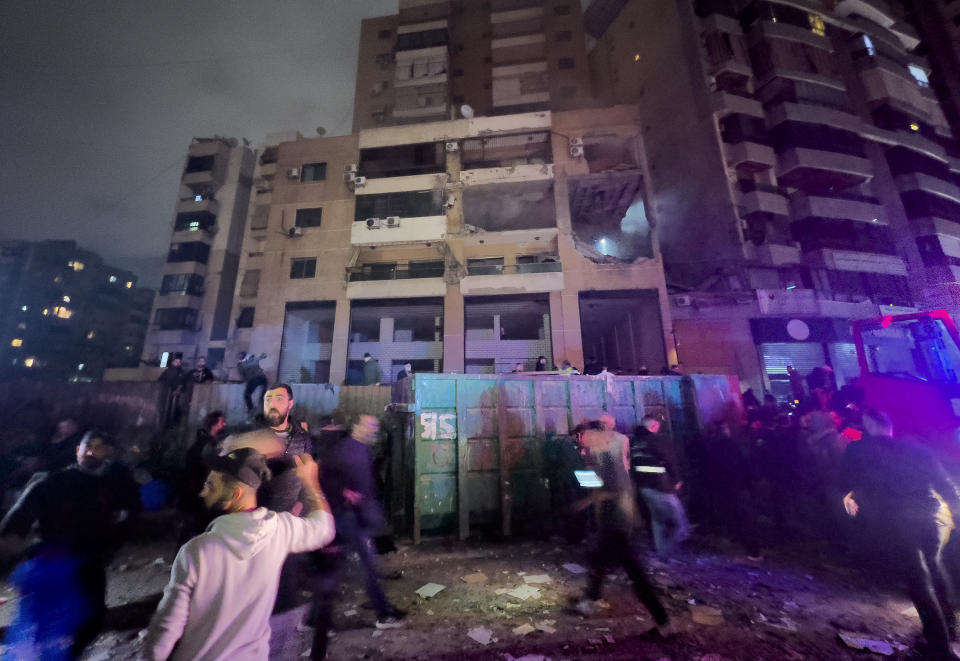 People gather outside a damaged building following a massive explosion in the southern suburb of Beirut, Lebanon, Tuesday, Jan. 2, 2024. The TV station of Lebanon's Hezbollah group says top Hamas official Saleh Arouri was killed Tuesday in an explosion in a southern Beirut suburb.(AP Photo/Hussein Malla)