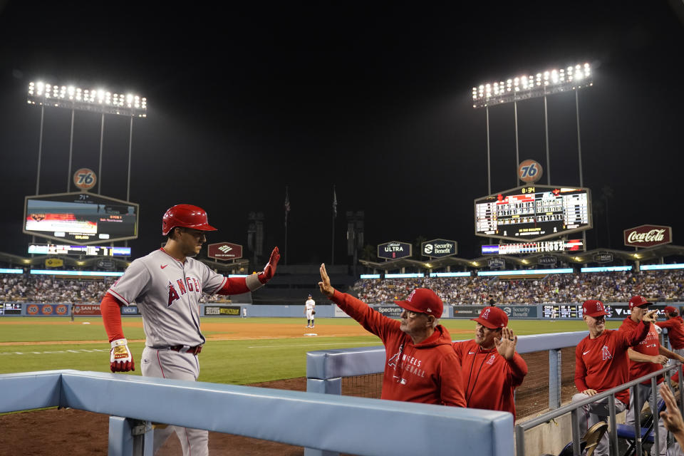 Los Angeles Angels' Jose Iglesias, left, is met in the dugout by manager Joe Maddon after Iglesias' solo home run during the fifth inning of a baseball game against the Los Angeles Dodgers on Friday, Aug. 6, 2021, in Los Angeles. (AP Photo/Marcio Jose Sanchez)