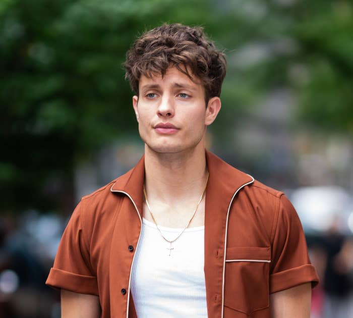 Closeup of Matt Rife outside in an open shirt and a tank top underneath