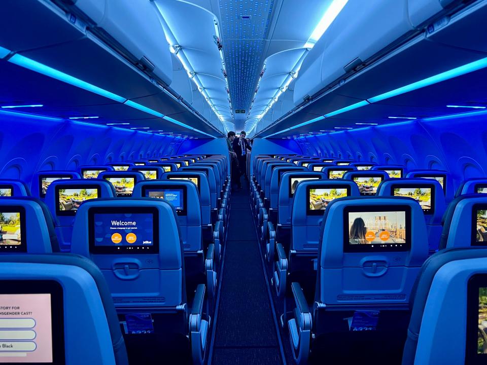 The inside of a JetBlue A321neoLR with blue lighting.