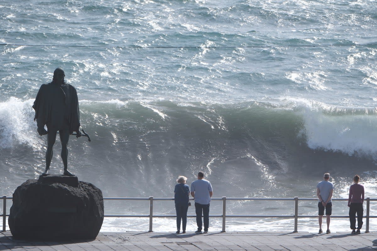 Onlookers watch the high waves breaking at Candelaria, Tenerife (EPA)