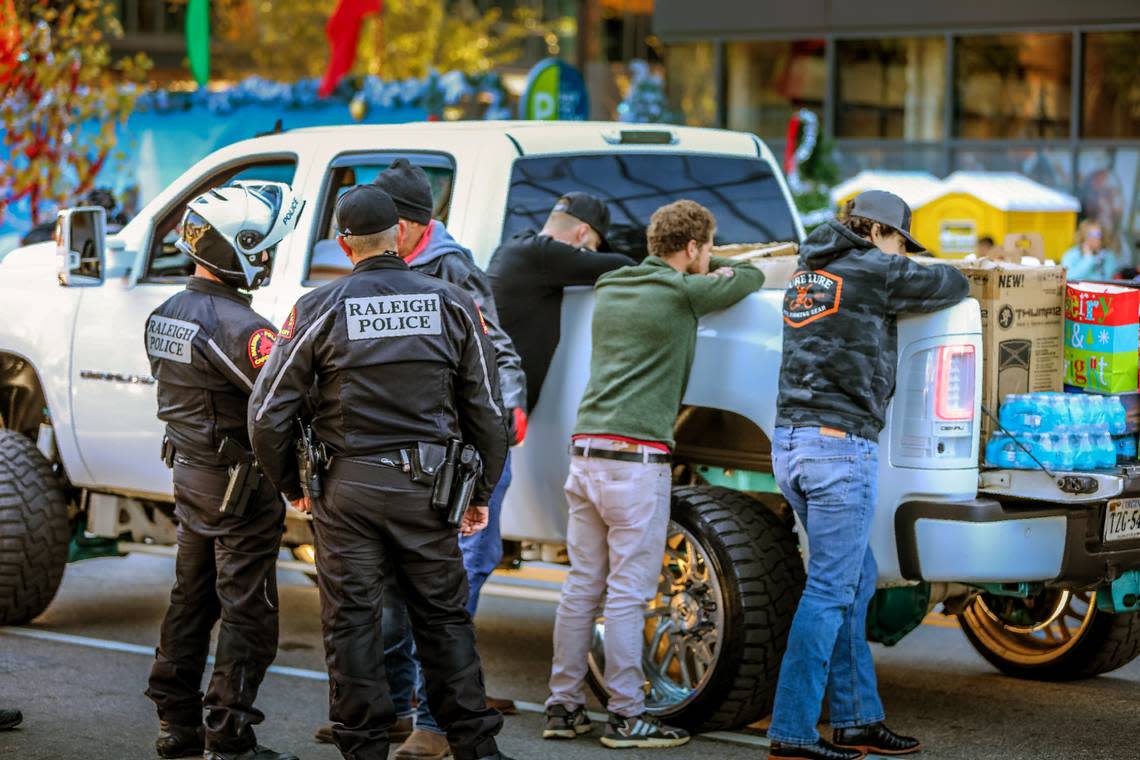 Three occupants of the truck that struck and fatally injured a young dancer in the Raleigh Christmas Parade are detained by police Saturday morning, Nov. 19, 2022. The driver of the truck, Landen Christopher Glass, 20, is at right. He was charged with misdemeanor death by motor vehicle, careless and reckless, improper equipment, unsafe movement, and carrying a firearm in a parade.