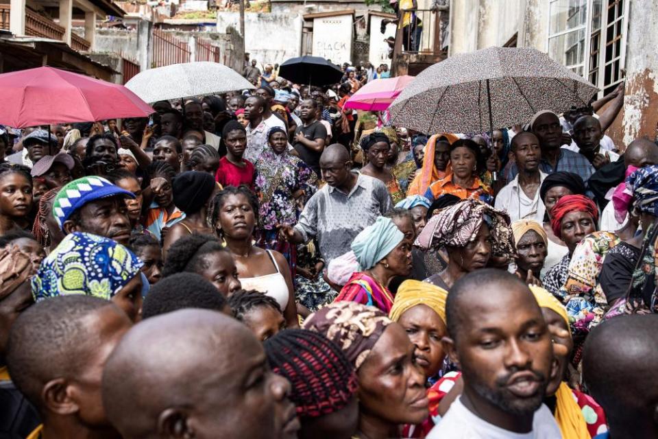 Voters gather at a polling station that opened seven hours late in Freetown on 24 June during the presidential vote.