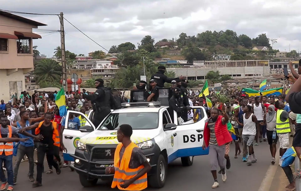 This video grab shows coup supporters cheering police officers in Libreville, Gabon, Wednesday Aug. 30, 2023. Mutinous soldiers speaking on state television announced that they had seized power in and were overturning the results of a presidential election that had seen Gabon President Ali Bongo Ondimba extend his family's 55-year hold on power. ( AP Photo/Betiness Mackosso)