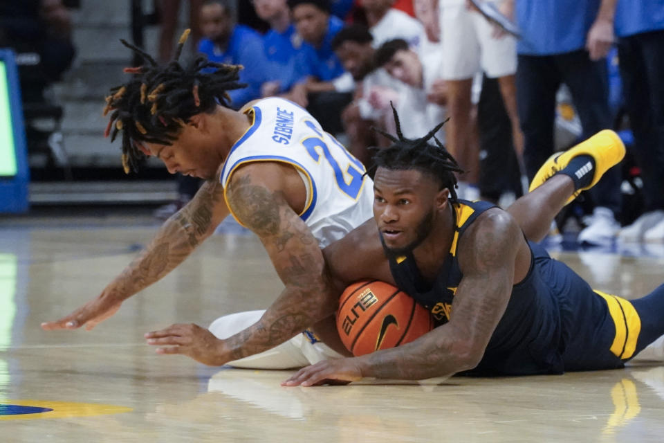 West Virginia's Joe Toussaint, right, and Pittsburgh's Nike Sibande, left, battle for the ball during the first half of an NCAA college basketball game, Friday, Nov. 11, 2022, in Pittsburgh. (AP Photo/Keith Srakocic)
