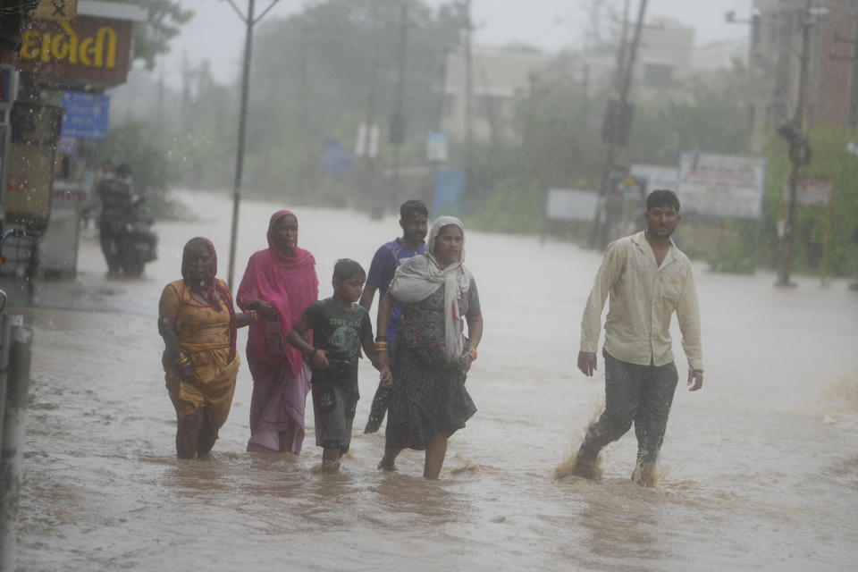 People wade through a flooded street following heavy winds and incessant rains after landfall of cyclone Biparjoy at Mandvi in Kutch district of Western Indian state of Gujarat, Friday, June 16, 2023. Cyclone Biparjoy knocked out power and threw shipping containers into the sea in western India on Friday before aiming its lashing winds and rain at part of Pakistan that suffered devastating floods last year. (AP Photo/Ajit Solanki)
