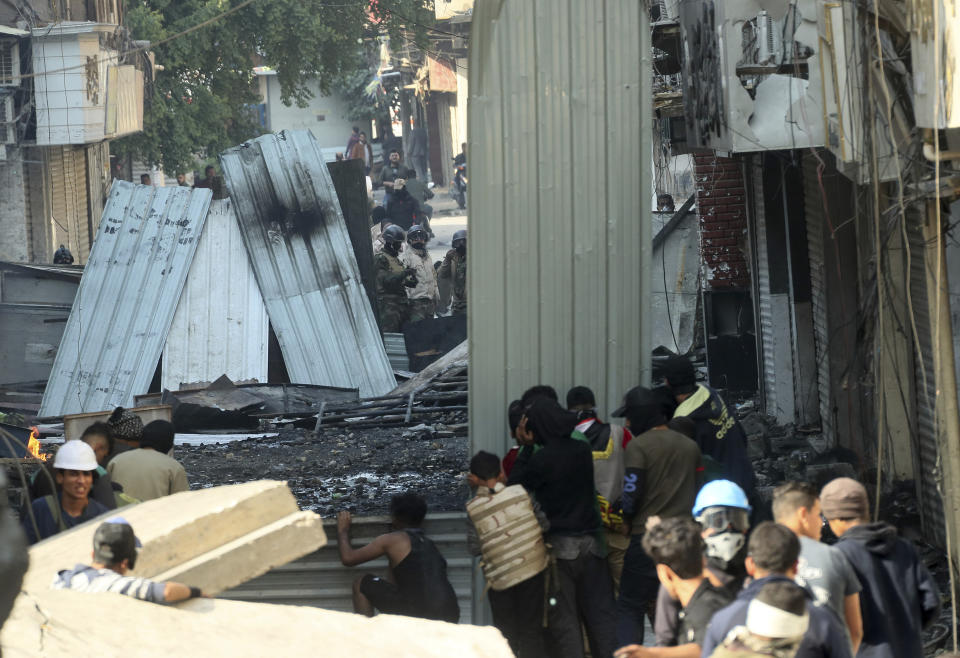 Anti-government protesters take cover during clashes with security forces in Baghdad, Iraq, Saturday, Nov. 30, 2019. (AP Photo/Hadi Mizban)