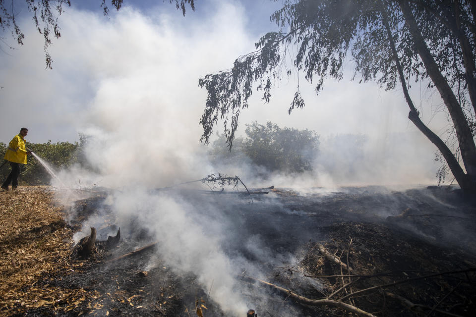 A firefighter attempts to extinguish a fire started by an incendiary device launched from the Gaza Strip, on the Israeli side of the border between Israel and Gaza, Monday, Aug. 24, 2020. Militants affiliated with Hamas have launched scores of incendiary balloons into southern Israel in recent weeks in a bid to pressure Israel to ease the blockade imposed since Hamas took control of the territory in 2007. The Israeli military said it struck militant targets in the Gaza Strip early on Monday, in response to the balloons launched into Israel the day before. (AP Photo/Ariel Schalit)