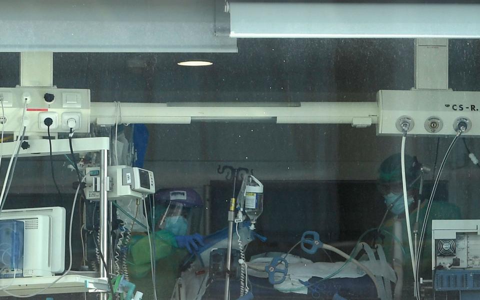 Healthcare workers in protective gear attend to a patient at La Paz hospital in Madrid -  Pierre-Philippe Marcou/AFP