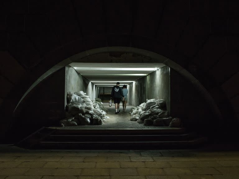 Una pareja camina por un túnel subterráneo cubierto de bolsas de arena para protegerse de los ataques, cuando está a punto de comenzar el toque de queda en Kiev el 16 de julio de 2022. 